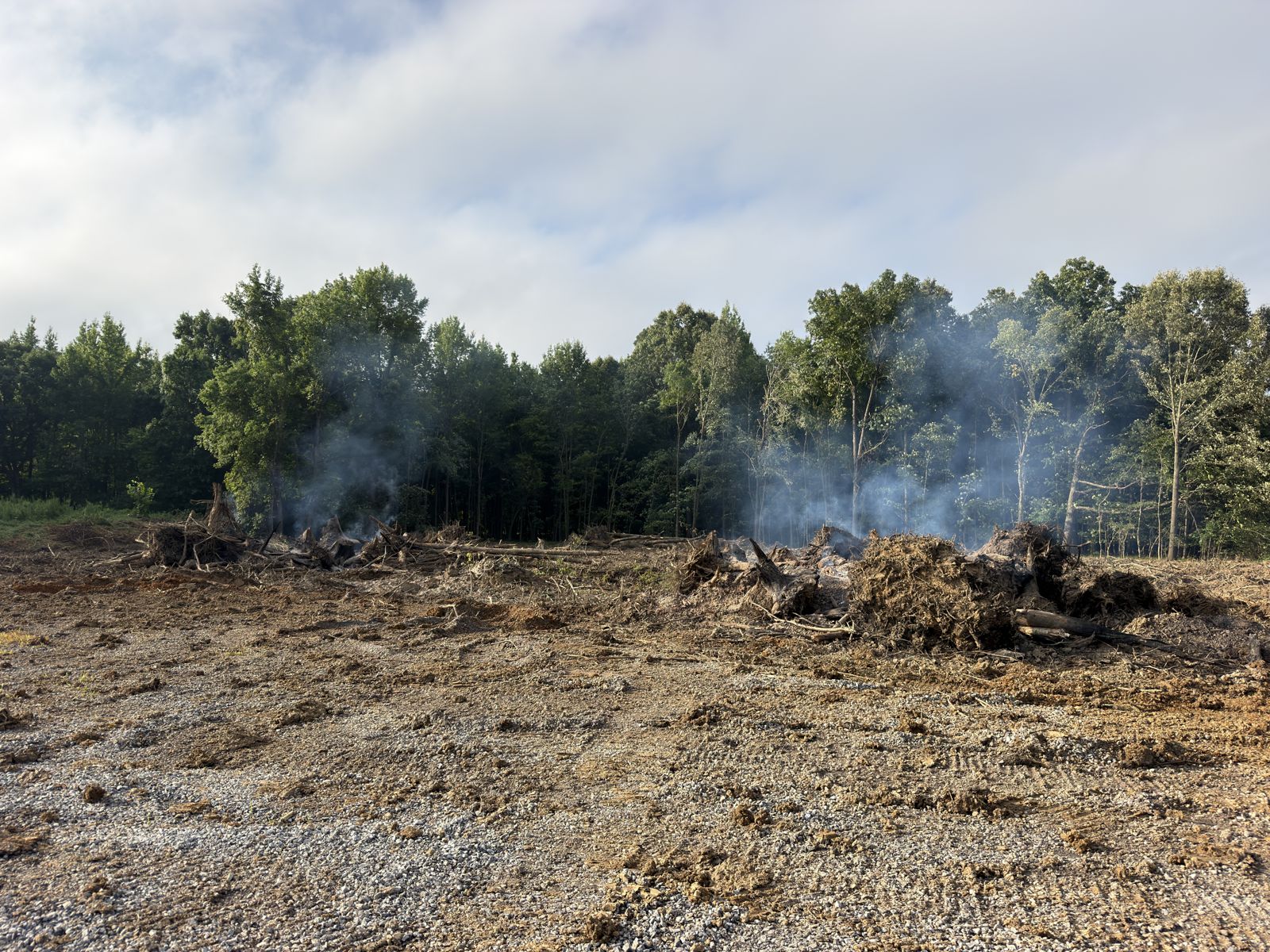 Land cleared and grubbed with burn piles smoking, ready for final grade in Western Kentucky