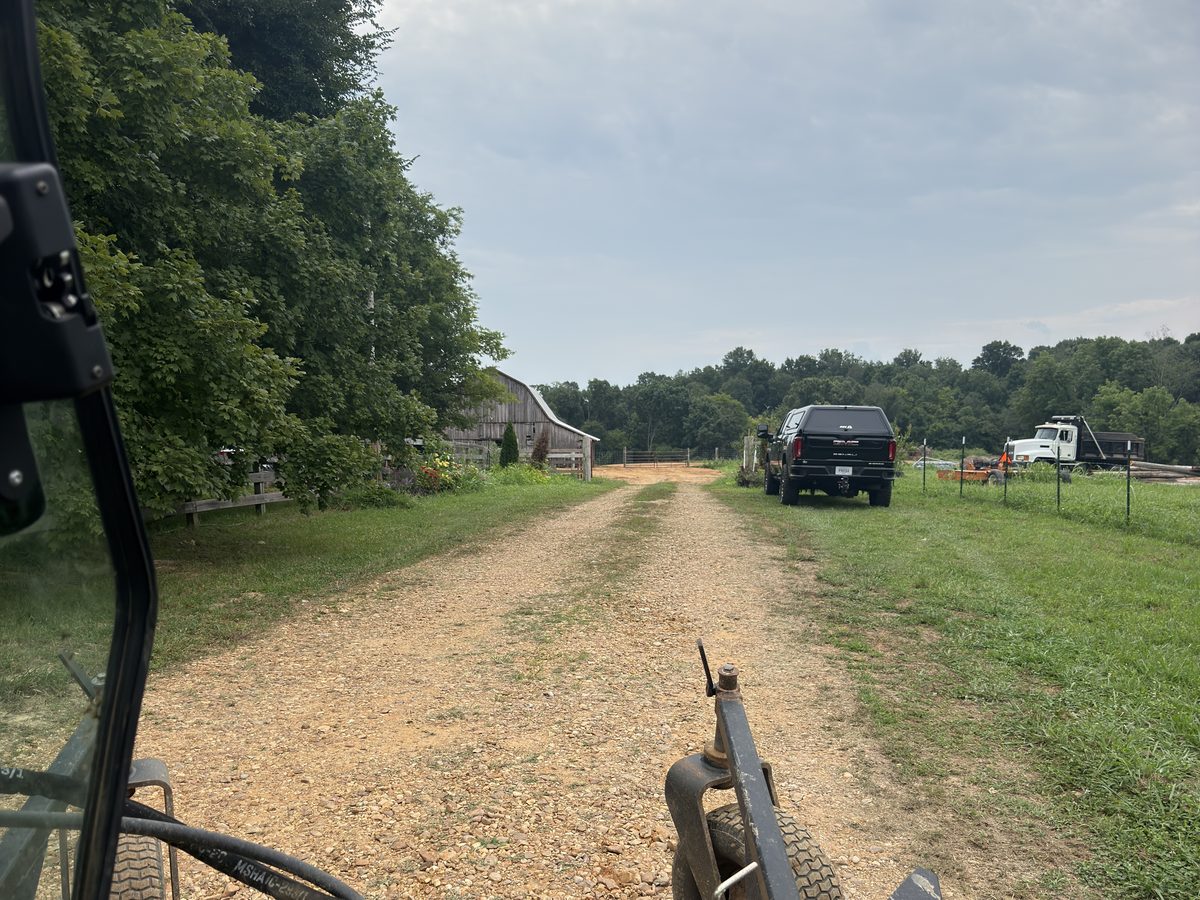 Gravel lane with grass growing through the center and rock driven into the dirt, before power raking, Western Kentucky